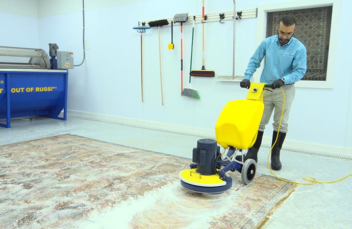 A person is using a carpet cleaning machine to clean a rug.