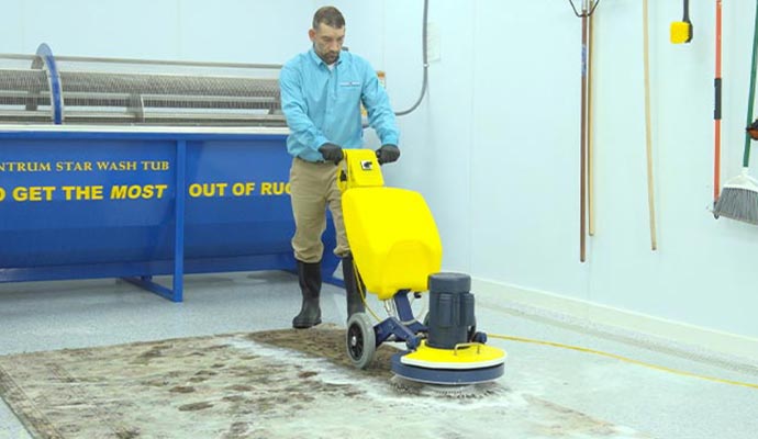 A person cleaning rug using professional equipment A person cleaning rug using professional equipment