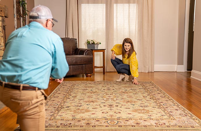 Homeowners inspect a waterproof rug pad to ensure it fits properly.