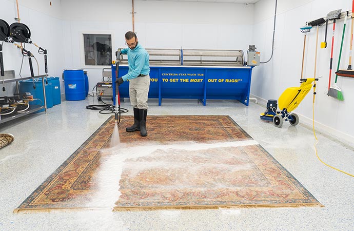 Professional worker using cleaning equipment to deep clean a dirty rug